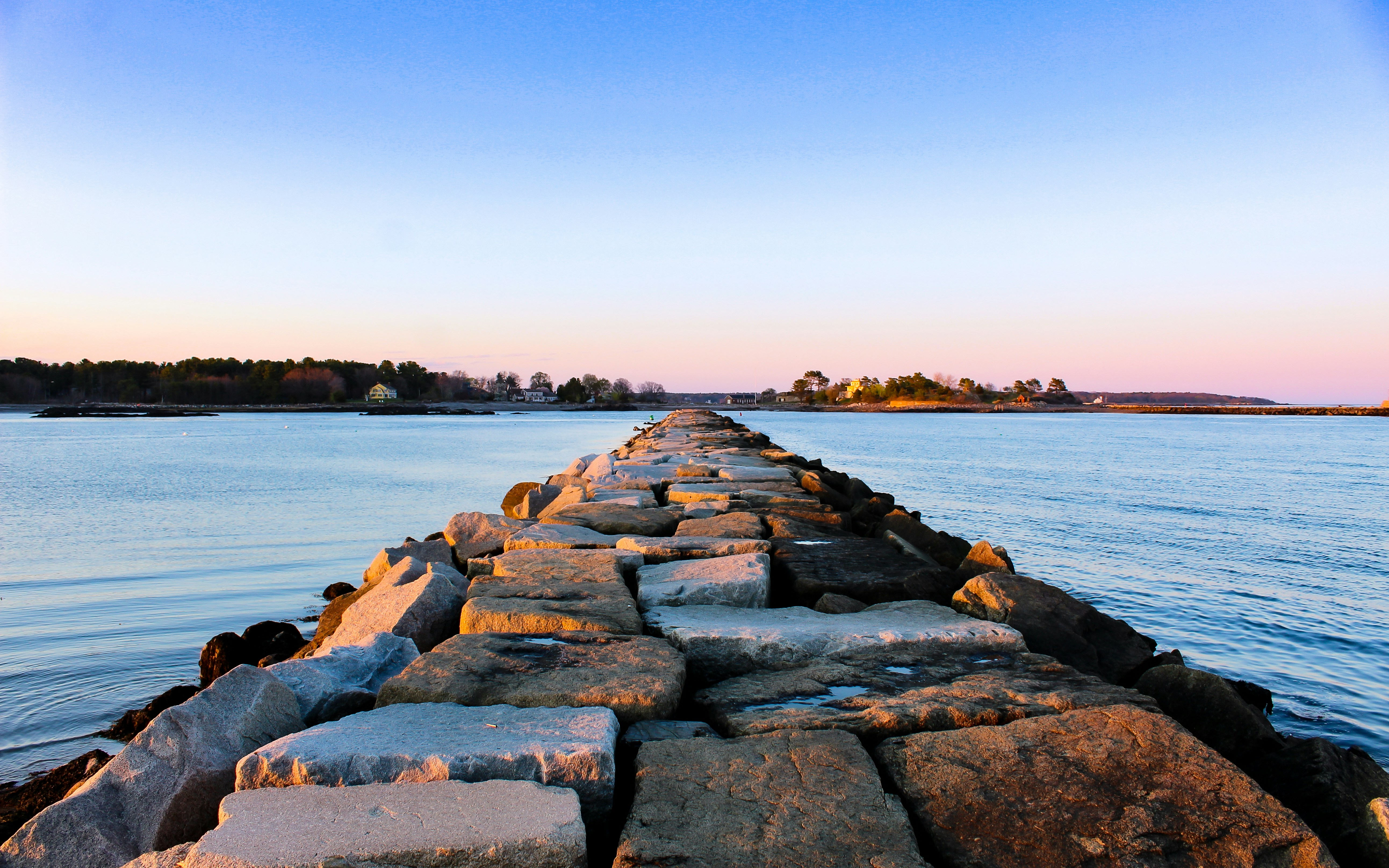 A granite breakwater running out into open water on the New Hampshire coast at first light.